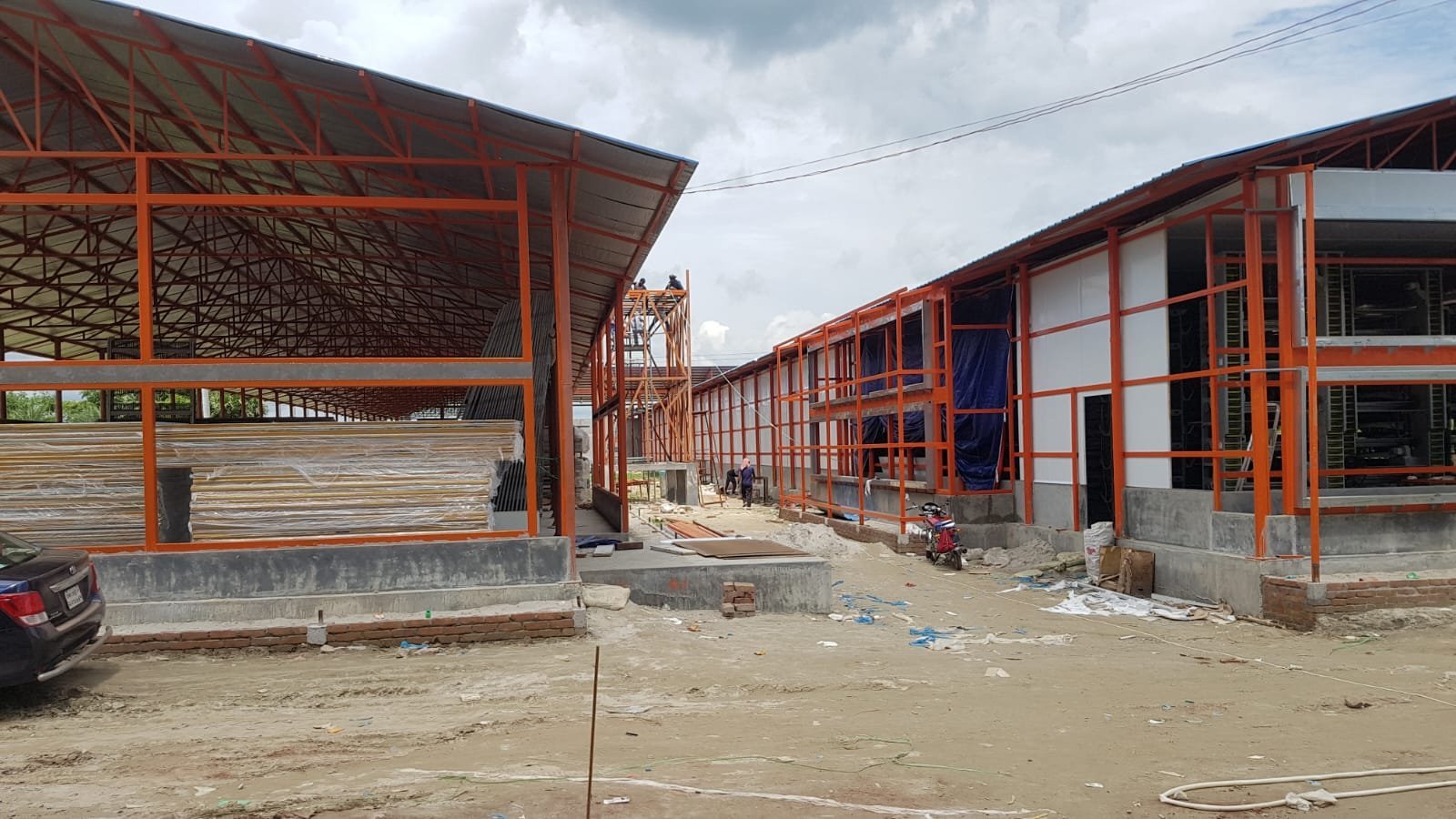 Orange steel-framed sheds under construction with white wall panels